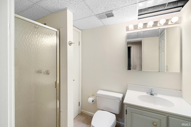 bathroom with vanity, toilet, a shower with shower door, and a drop ceiling