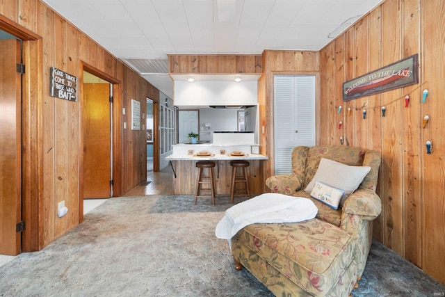 sitting room with light carpet and wood walls