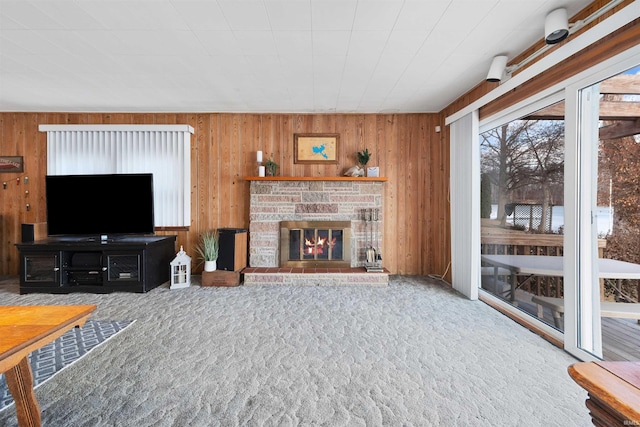 living room with a fireplace, wooden walls, and carpet