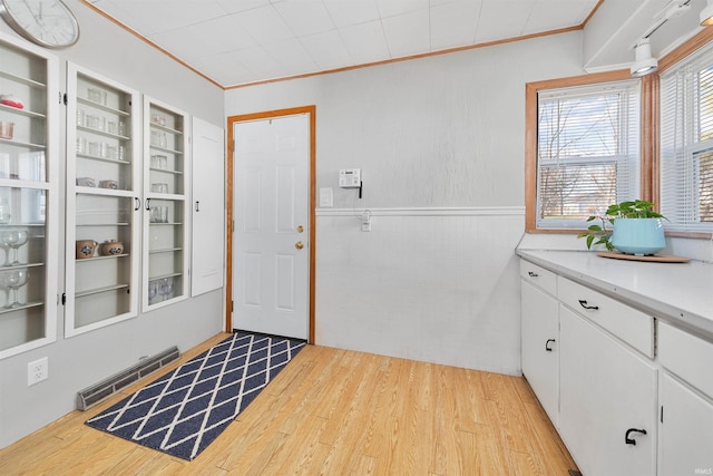 entryway featuring built in shelves, ornamental molding, and light wood-type flooring