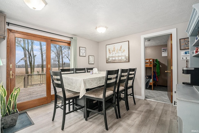 dining space featuring light hardwood / wood-style flooring and a textured ceiling