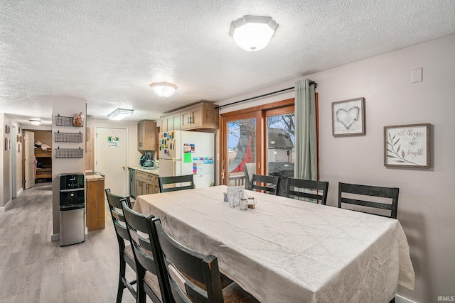 dining space with light hardwood / wood-style flooring and a textured ceiling