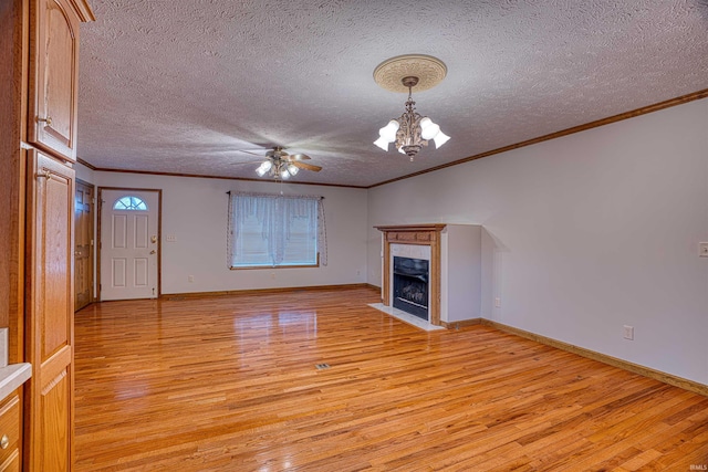 unfurnished living room with a textured ceiling, light wood-type flooring, ornamental molding, a fireplace, and ceiling fan with notable chandelier