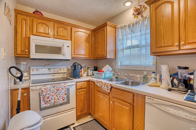 kitchen featuring white appliances, sink, and a textured ceiling