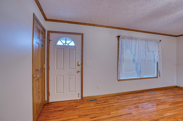 foyer featuring ornamental molding, light hardwood / wood-style floors, and a textured ceiling