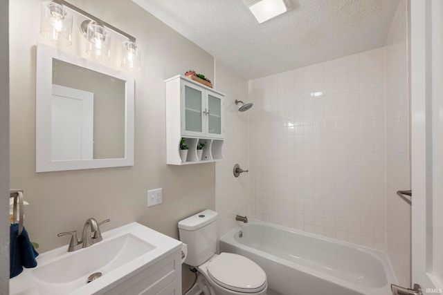 full bathroom featuring vanity, tiled shower / bath, toilet, and a textured ceiling