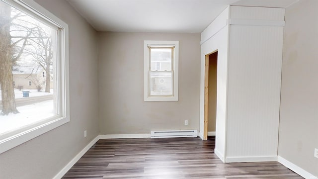 spare room with dark wood-style floors, a baseboard radiator, and plenty of natural light