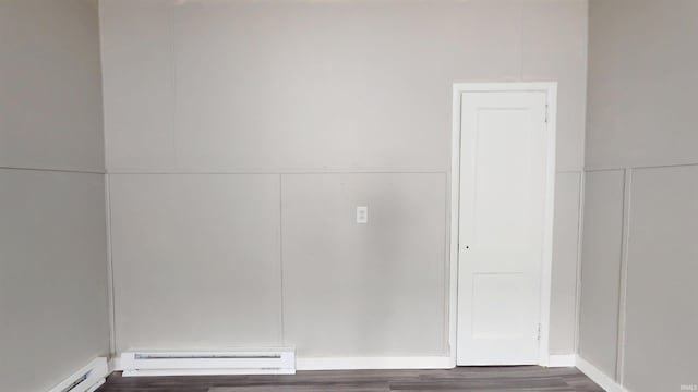 interior space with dark wood finished floors and a baseboard heating unit