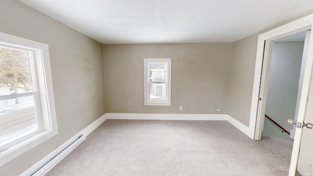 spare room with baseboards, a baseboard heating unit, and light colored carpet