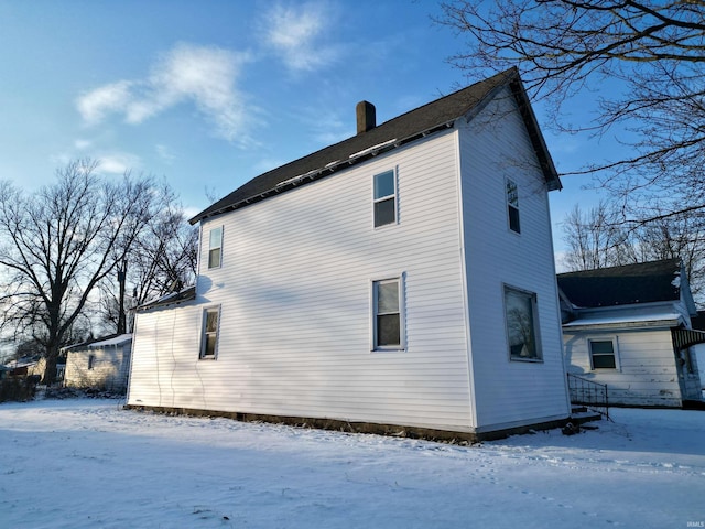 snow covered property with a chimney