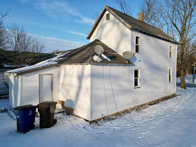 snow covered property with a chimney