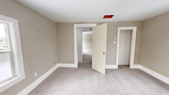 unfurnished bedroom with multiple windows, light carpet, and baseboards