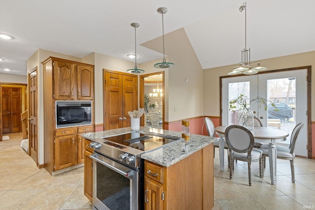 kitchen with pendant lighting, black microwave, stainless steel range, a kitchen island, and vaulted ceiling