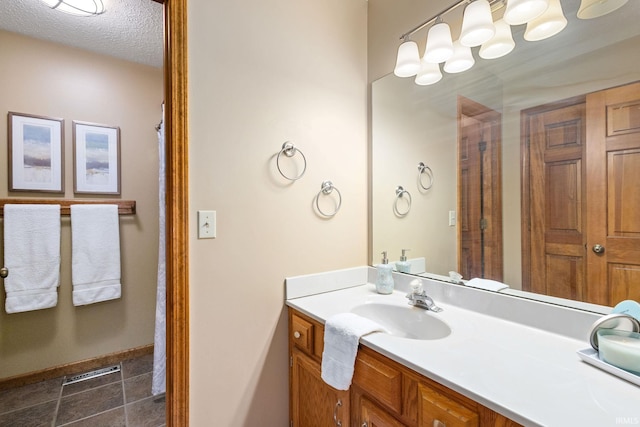 bathroom with tile patterned flooring, vanity, and a textured ceiling