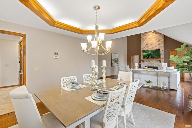 dining space featuring dark hardwood / wood-style flooring, a tray ceiling, a fireplace, and crown molding