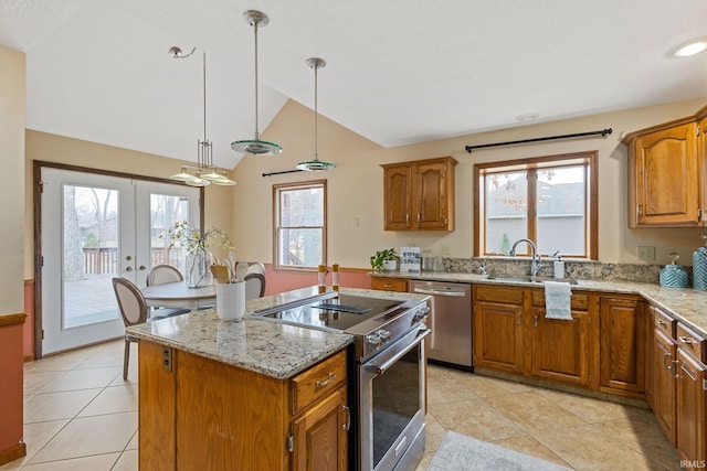 kitchen with sink, stainless steel appliances, a center island, light stone countertops, and decorative light fixtures