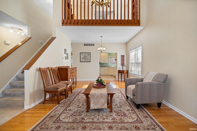 living room with wood-type flooring, a towering ceiling, and a chandelier