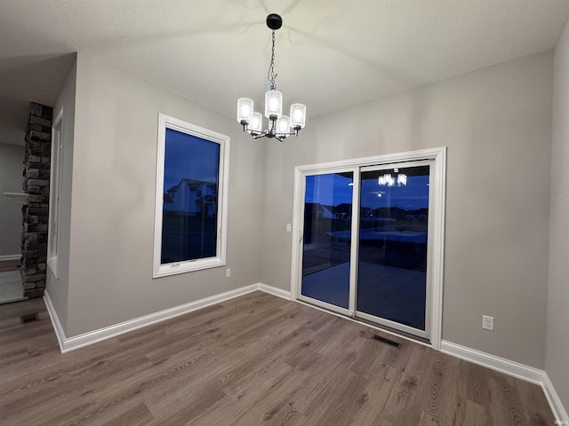 empty room featuring hardwood / wood-style flooring and a notable chandelier