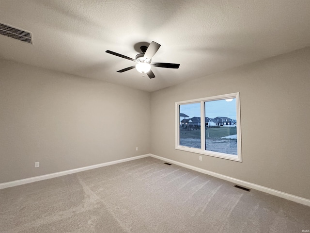 spare room featuring ceiling fan, carpet, and a textured ceiling