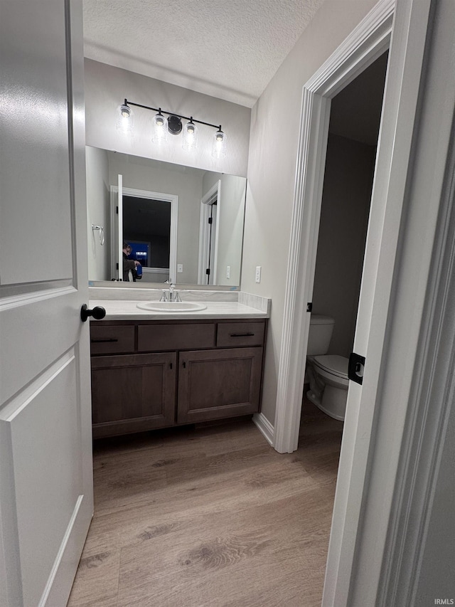 bathroom with vanity, hardwood / wood-style floors, a textured ceiling, and toilet