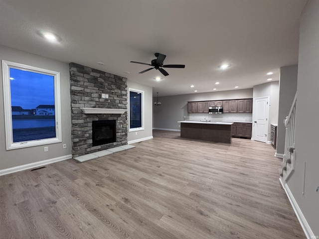 unfurnished living room with ceiling fan, a fireplace, and light hardwood / wood-style floors