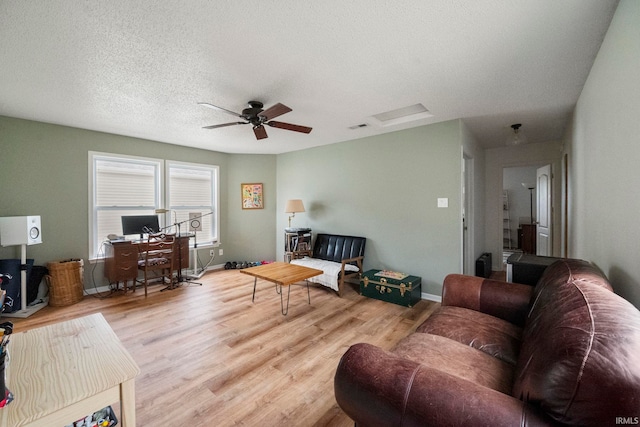 living room featuring ceiling fan, a textured ceiling, and light hardwood / wood-style floors