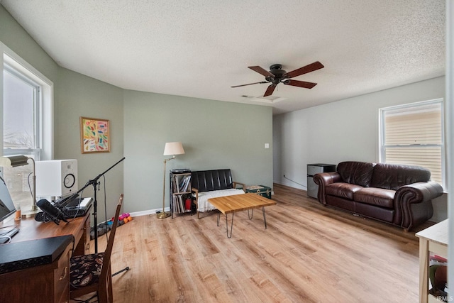 living room with a textured ceiling, light hardwood / wood-style floors, and a healthy amount of sunlight