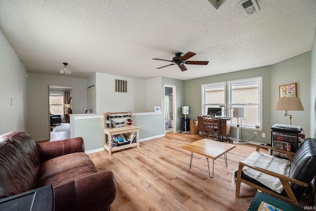 living room featuring ceiling fan, plenty of natural light, a textured ceiling, and light wood-type flooring