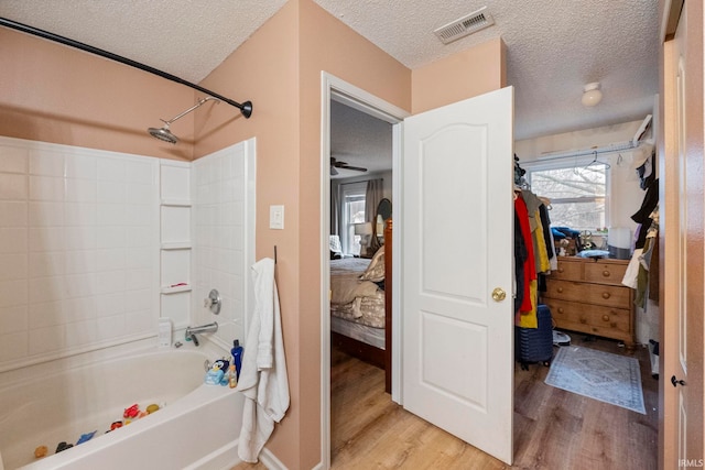 bathroom with hardwood / wood-style flooring, a textured ceiling, and shower / bath combination