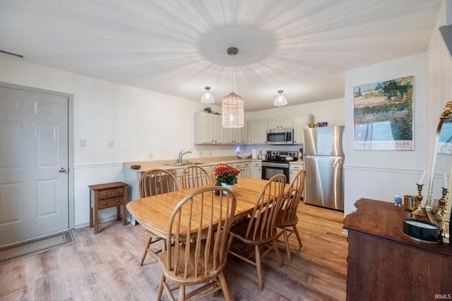 dining area with sink and light wood-type flooring