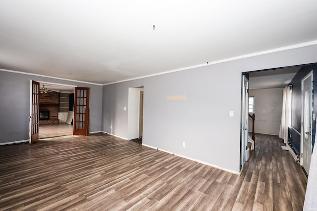 unfurnished living room featuring dark wood-type flooring, a fireplace, french doors, and crown molding