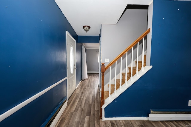 stairway with baseboard heating and wood-type flooring