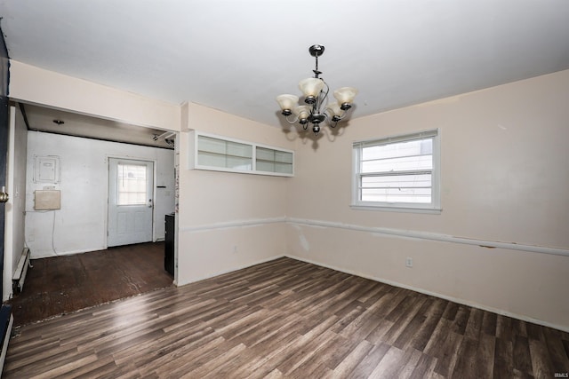 empty room featuring a notable chandelier, dark wood-type flooring, a baseboard radiator, and a healthy amount of sunlight