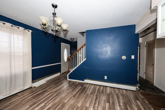 unfurnished room with dark wood-type flooring, a baseboard radiator, and a notable chandelier