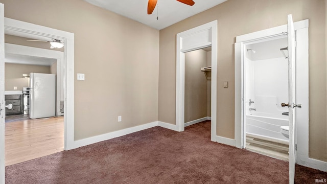 unfurnished bedroom featuring carpet flooring, ensuite bathroom, and white fridge