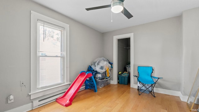 game room with ceiling fan and light wood-type flooring