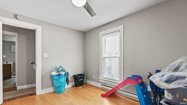 playroom featuring baseboard heating, ceiling fan, and hardwood / wood-style floors