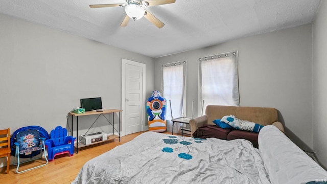 bedroom with ceiling fan, wood-type flooring, and a textured ceiling