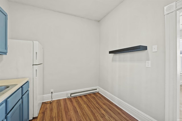 kitchen with blue cabinets, white fridge, hardwood / wood-style floors, and baseboard heating