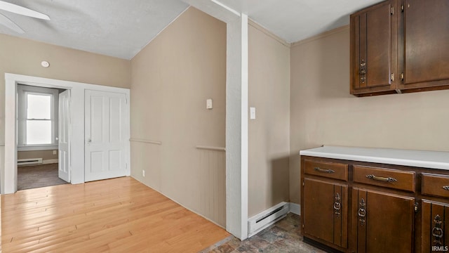 kitchen featuring dark brown cabinetry, a baseboard heating unit, and light hardwood / wood-style floors