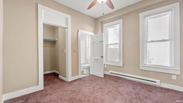 unfurnished bedroom featuring ensuite bath, a baseboard heating unit, a spacious closet, light colored carpet, and a closet