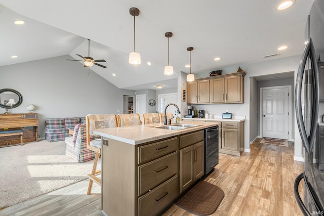 kitchen featuring decorative light fixtures, sink, a breakfast bar area, black appliances, and a center island with sink