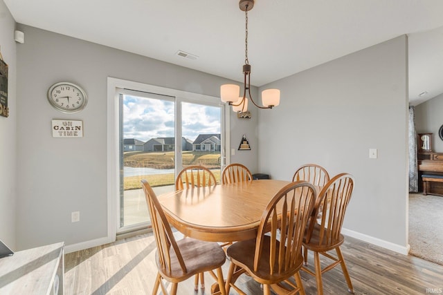 dining space with hardwood / wood-style floors and a chandelier