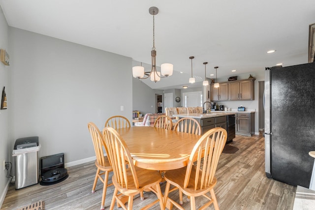 dining area featuring sink, light hardwood / wood-style floors, and a chandelier