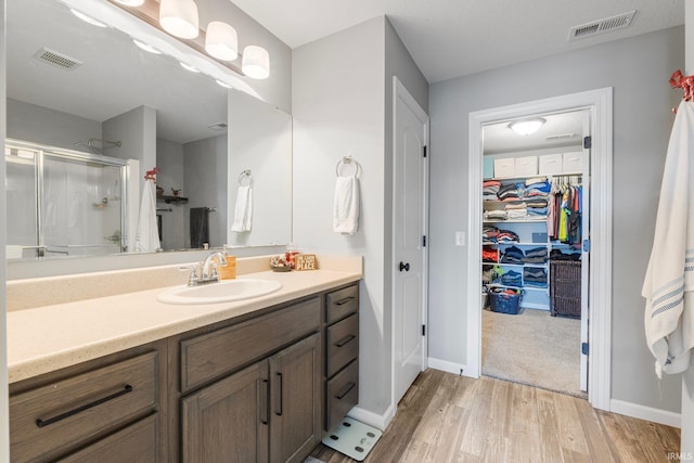 bathroom featuring walk in shower, vanity, and wood-type flooring