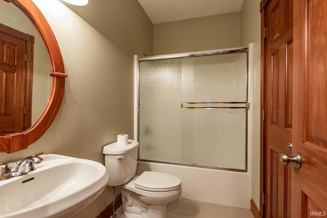 full bathroom featuring toilet, tile patterned floors, combined bath / shower with glass door, and sink