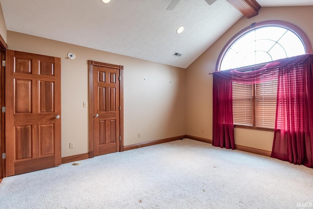 carpeted empty room featuring vaulted ceiling with beams and a textured ceiling