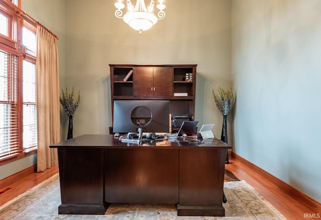 office area with a healthy amount of sunlight, an inviting chandelier, and light hardwood / wood-style flooring