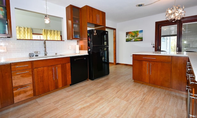 kitchen with pendant lighting, sink, decorative backsplash, black appliances, and light stone countertops