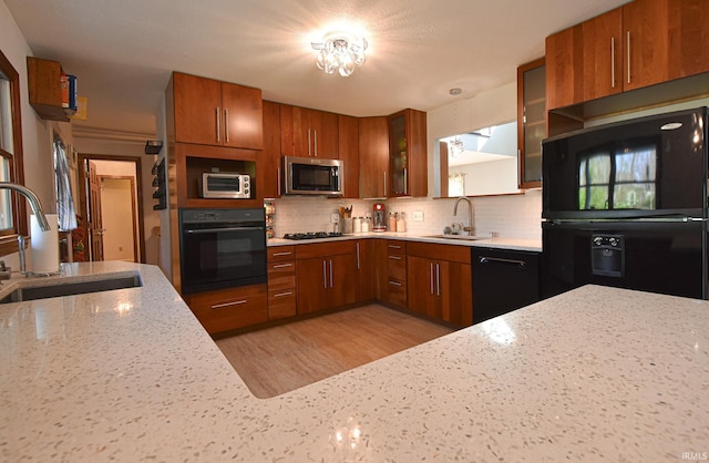 kitchen with backsplash, decorative light fixtures, sink, and black appliances